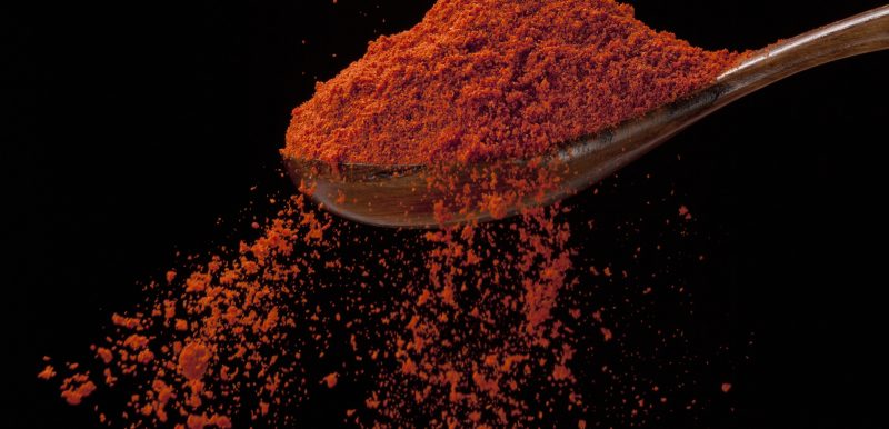 Cayenne pepper is flowing-photographed on black background